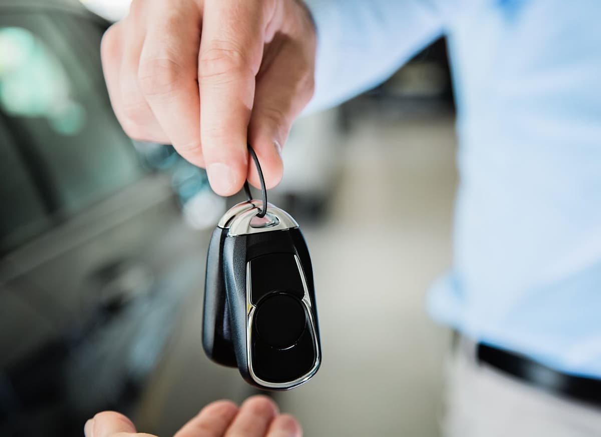 Fahrzeugschlüssel wird bei der Übergabe an den Überführungsfahrer gereicht